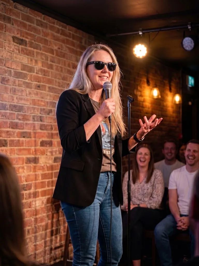A comedian at the mic in a small club, the front row laughing