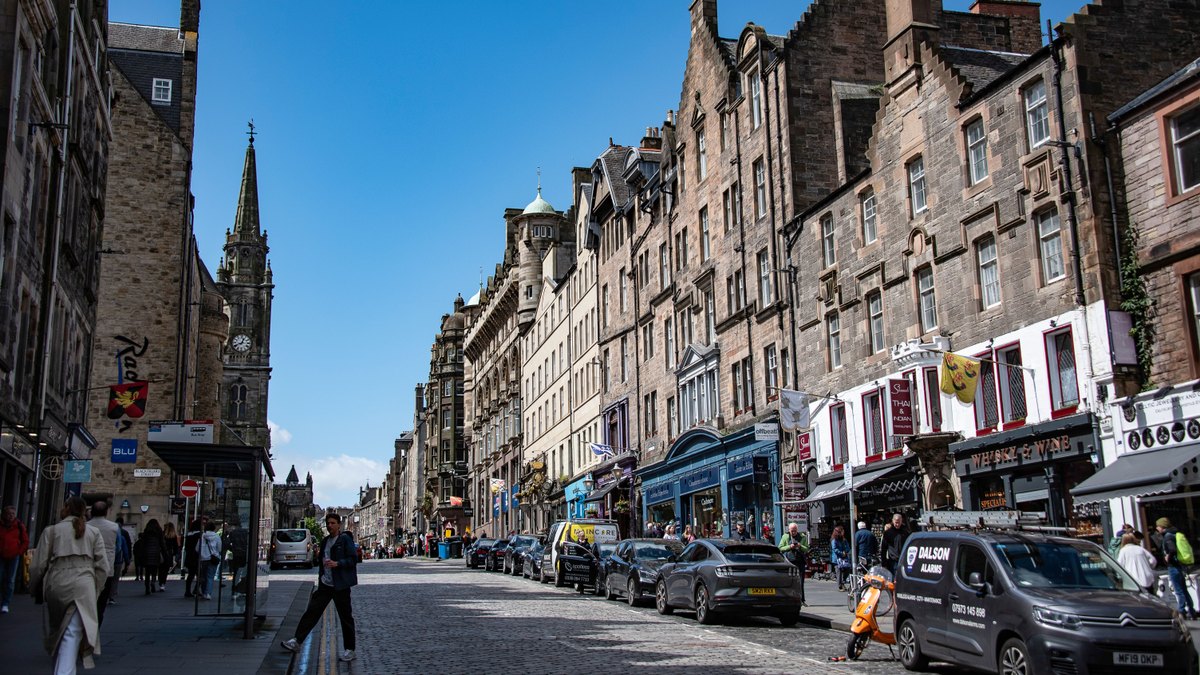 Explore the vibrant historic Royal Mile street in Edinburgh, Scotland with shops and architecture.